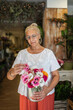 © Lupe Rodriguez/Stocksy - Florist carrying flowers to arrange in a vase