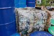 © Heng Yu/Stocksy - Compressed Plastic Bottles Next to Blue Barrels