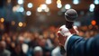 © ninakosh - Speaker holds microphone in front of engaged audience at evening event in well-lit venue