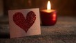 © ninakosh - Heart-shaped card with glitter next to a candle glowing softly in a dimly lit setting