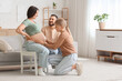 © Pixel-Shot - Young happy pregnant woman sitting on chair with her husband and doula at home