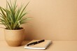 © azwan - Potted plant with notebook and pen on natural brown background with copy space