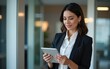 © Susan - Latin Hispanic mature adult professional business woman looking at online trade app. European businesswoman CEO holding digital tablet using fintech tab application standing at workplace in office.