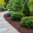 © Raden - A well-maintained garden path winds through a vibrant array of green shrubs and trees, nestled amongst a bed of rich brown mulch.