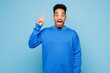 © ViDi Studio - Young man of African American ethnicity wears sweatshirt casual clothes holding index finger up with great new idea isolated on plain pastel light blue background studio portrait. Lifestyle concept.