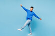 © ViDi Studio - Full body young man of African American ethnicity wear sweatshirt casual clothes listen to music in headphones raise up hands dance isolated on plain pastel light blue background. Lifestyle concept.