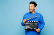 © ViDi Studio - Young man of African American ethnicity wear sweatshirt casual clothes hold in hand classic black film making clapperboard isolated on plain pastel light blue cyan background studio Lifestyle concept