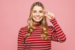 © ViDi Studio - Young smiling woman wear red striped sweatshirt casual clothes hold in hand cover eye with invisible transparent aligners, invisalign dental braces isolated on plain pink background Lifestyle concept