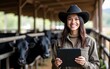 © Ryan - Portrait of black cow breeder with tablet standing at cow's ranch and smiling at camera. High quality