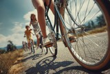 Sunny road scene featuring a family biking on asphalt, viewed from a low angle close-up focusing on a bicycle wheel