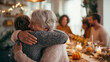 © Lara - Elderly woman hugging younger person during Thanksgiving dinner celebration. Grandparents hugging grandchildren on holiday