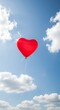 © Upin - A heart-shaped red balloon soars against a vibrant blue sky dotted with fluffy white clouds.