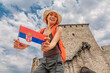 © EdNurg - Happy tourist holding Serbian flag visiting the medieval fortress on top of a hill near Vrsac in Serbia