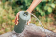 © EdNurg - Woman filling her reusable water bottle at a public drinking fountain, promoting hydration and sustainability