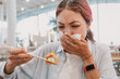 © EdNurg - Young woman is holding a sushi roll with chopsticks and covering her nose with a napkin, expressing disgust