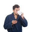 © 1STunningART - Portrait of sleepy young man messy hair, wears blue bathrobe, drinking coffee from his cup and speking on phone isolated on white background.
