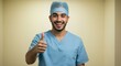 © Pluseight - Smiling young male healthcare professional in scrubs and cap giving a positive thumbs up, symbolizing approval and good health