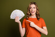 © deagreez - Smiling young woman holding fan of dollars, pointing towards wealth and financial success, promoting savings or rewards
