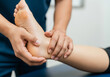 © Peeradontax - A close-up of a physical therapist or podiatrist examining and treating a patient's foot and ankle.