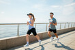 © muse studio - Couple enjoys a morning run on waterfront boardwalk