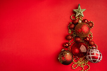 Wall Mural - christmas tree shape made of red and gold ornaments with a glitter star on top, on a red background.