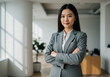 © Abida - Confident businesswoman in a modern office confidently poses with arms crossed, radiating professionalism and success.