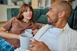© we.bond.creations - Young multi-ethnic couple relaxing together on the floor by the sofa, drinking coffee and chatting