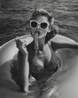 © Maria - Glamorous 1950s Italian woman eating spaghetti on a floatie on the beach, black and white