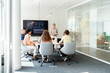 © Santi Nuñez/Stocksy - Business team meeting in modern office with interactive whiteboard