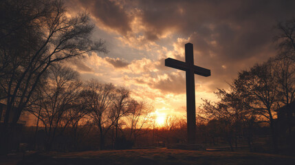 Wall Mural - large wooden cross stands silhouetted against dramatic sunset, surrounded by trees. sky is filled wi