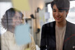 © Jovo Jovanovic/Stocksy - Two smiling colleagues brainstorm ideas on a glass board.