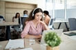 © Santi Nuñez/Stocksy - Focused employee working with headphones in a multicultural office