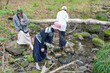 © Masakazu Tokashiki - A group of people are walking through a forest and one woman is looking at the water