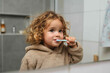 © Duckai - Girl Brushing Teeth While Wearing Brown Hoodie in Morning Bathroom Routine Focused on Healthy Habits and Daily Hygiene