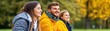 © watcharee - Three young adults laughing and enjoying a moment outdoors, surrounded by autumn foliage, wearing cozy jackets.