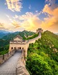 © AuraAesthetic - Elevated view of the Great Wall of China during a vibrant sunset, surrounded by rolling green hills and a dynamic sky