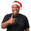 © SimpleDesignStudio - Happy young adult Black woman wearing a festive Santa hat and black apron, giving a cheerful thumbs up gesture, celebrating the Christmas holiday with a positive and friendly expression.