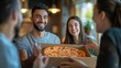 © Can Berkol - young man presenting pizza box to friends in modern cafe
