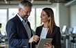 © fu - Team leader explain trainee working process using tablet pc computer. Two professional business people working together. Partners mature man, woman discussing project in office workplace. Copy space