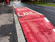 Bus lane signage on a pavement in Manchester, UK during daytime