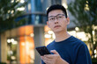 © zhu difeng - man in a blue T-shirt holds a phone in an urban area