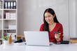 © Phimwilai - Asian freelancer paying online with credit card on laptop in home office