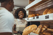 © Dragana Gordic - Delighted Baker Holding Fresh Bread While Engaging With a Smiling Customer
