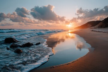 Wall Mural - Breathtaking sunset illuminates serene beach with gentle waves lapping at golden sand and clouds reflecting on tranquil water