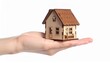 © fkdesignstd - Hand holding miniature wooden house against white backdrop, symbolizing home ownership and real estate investment, conveying security and aspiration.