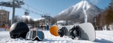 Winter sports gear arranged on snow with ski lifts in background and mountain peak under bright blue sky