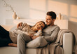 © AdiAgus - Couple relaxing on couch with dog, enjoying intimate moment.