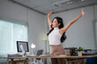 © Wasana - Asian businesswoman stretching arms at workplace after work is done