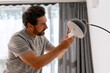 © Maria Vitkovska - Man changing light bulb in modern lamp at home