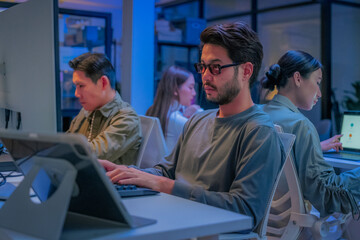 young Asian software development manager leads a late-night office discussion with his executive team, mentoring developers and analyzing source code to guide programming and project development